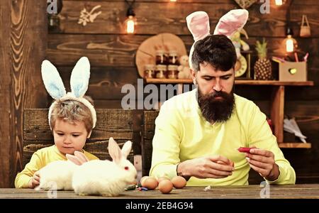 Father and son painting Easter eggs. Rabbits family with bunny ears. Stock Photo