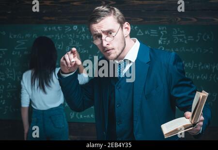 Young teacher professor explaining mathematic formula, giving a lecture at university. Stock Photo
