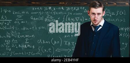 Intelligent teacher in suit and glasses. Young professor explaining mathematic formula. Stock Photo