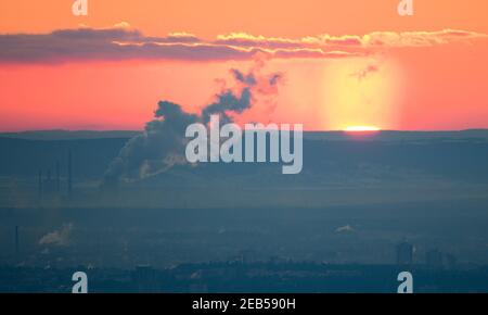 Hessen, Königstein-Falkenstein, 12 Feb 2021:The sun rises in the early morning on the horizon behind a power plant, from which white steam rises. Photo: Arne Dedert/dpa Credit: dpa picture alliance/Alamy Live News Stock Photo