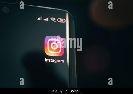 Barnaul. Russia. February 9, 2021: Instagram app icon on the smartphone screen with visible pixels and the finger about to launch it. Stock Photo