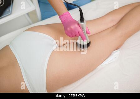 Top view cropped shot of a cosmetologist using rf-lifting device on buttocks of female client Stock Photo