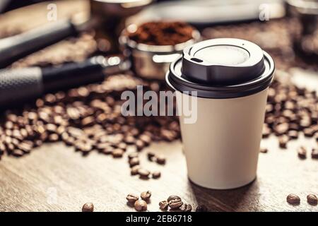 Paper takeaway cup with a plastic lid with a coffee with coffee beans and ground coffee in the background. Stock Photo