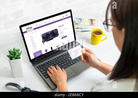 Buying a graphics card online concept. Girl holds a credit card and buys through ecommerce web site Stock Photo