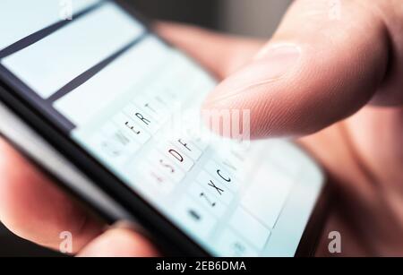 Text message with smartphone. Man texting sms with phone. Catfish or mobile scam. Digital instant messaging chat. Macro close up of keyboard. Stock Photo