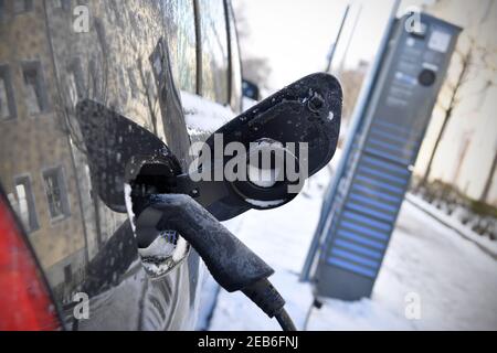 An electric car is charged during a cold winter day in the snow in ...