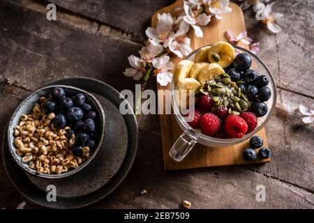Yogurt with granola and fresh blueberries, in glass bowl over old wood background. Vintage effect. Stock Photo