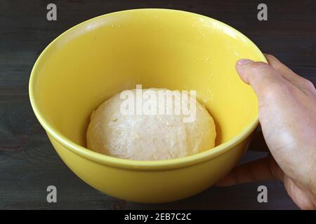 Hand placing a bowl of kneaded dough on the table to let it rises before baking Stock Photo