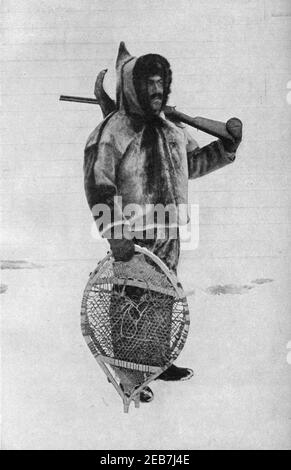 An early 20th century photo of a Labrador Inuit clad in a traditional seal skin parka with round Innu snowshoes and carrying a hunting rifle circa early 1900s Stock Photo