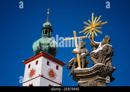 Tirschenreuth, Germany. 12th Feb, 2021. The steeple of the city's parish church of the Assumption of the Virgin Mary can be seen behind Christian statues on Maximilianplatz. According to the Bavarian state government, the more contagious corona virus variant from Great Britain has already gained the upper hand in some eastern Bavarian regions among commuters from the Czech Republic. The proportion of the mutated variant in positive corona tests is around 70 percent in Tirschenreuth, Bavarian Prime Minister Söder (CSU) said on 'Markus Lanz'. Credit: Nicolas Armer/dpa/Alamy Live News Stock Photo