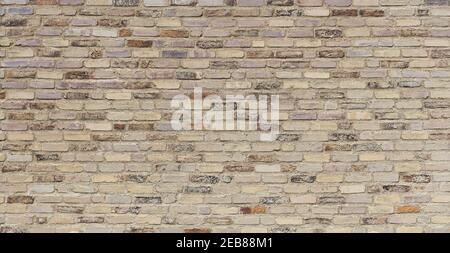 Old, beige brown, very roughly crafted brick wall Stock Photo