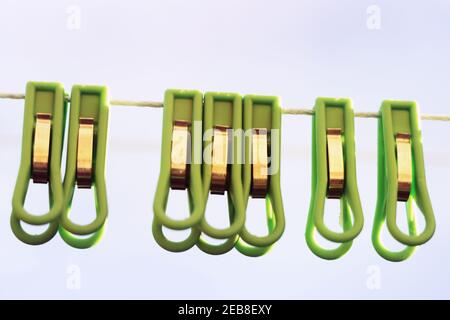 laundry clothespins of green plastic, metal clamping. hanging on clothesline twine outdoors Stock Photo