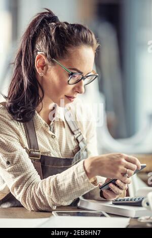 Beautiful business owner works with a calculator to do bookkeeping wearing glasses. Stock Photo