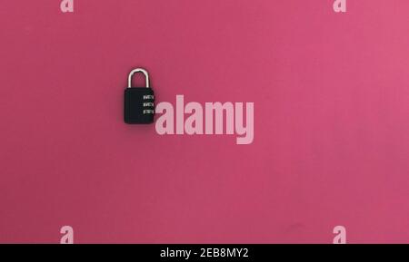 detail of a black padlock with a combination of numbers closed on pink background security concept Stock Photo