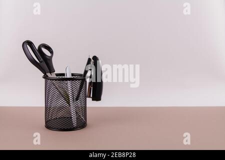 a scissors and a stapler with a handle in an organizer on a white office table Stock Photo