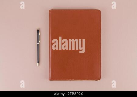 notebook in a brown leather cover lies with a pen on the office table Stock Photo
