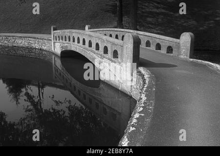 Black and white curved cement arch bridge over water for pedestrians Stock Photo