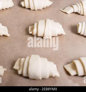 Raw group of croissants close-up on baking paper. Stock Photo