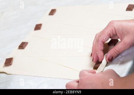 Hands of pastry chef making croissants with chocolate, close up. Stock Photo