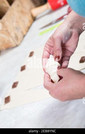 Woman's hands making croissants with chocolate, at home kitchen. Stock Photo