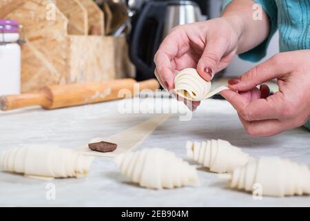 Woman's hands making croissants at home with chocolate. Stock Photo