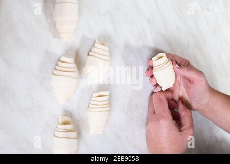 Pastry chef hands, making croissants on a white table. Stock Photo