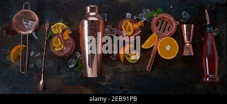 Panorama banner for alcoholic cocktails or bar with stylish copper shaker and implements on a black background with served drinks in glasses and fresh Stock Photo