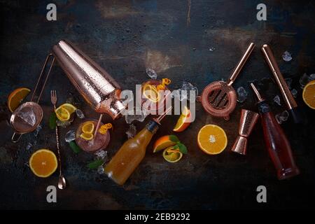 Cocktails or pub flat lay still life with copper bar equipment, chilled alcoholic beverages in glasses and sliced fresh oranges for garnishes scattere Stock Photo