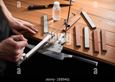 Man sharpening a Japanese knife with Damascus steel using a manual machine Stock Photo