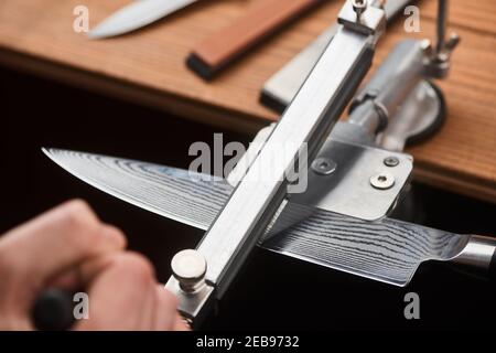 Close-up on man's hand using a manual machine to sharpen a Japanese knife Stock Photo