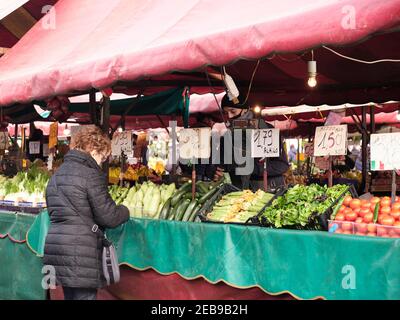 Turin, Italy - february 2021: a woman buys fresh vegetables at the counter of the historic market of Porta Palazzo Stock Photo