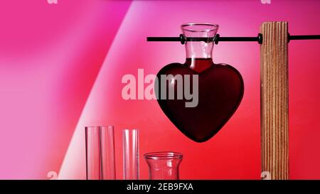 Valentines day potion. Love potion in the shape of a heart on a pink background. Chemical flasks. Stock Photo