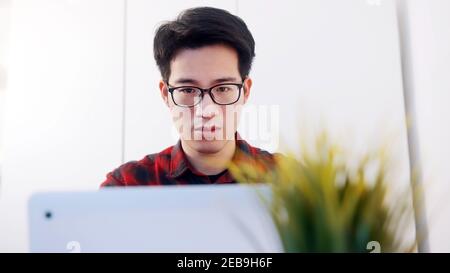 Portrait of young asian man using laptop to at home. Distance learning concept or remote work concept. High quality photo Stock Photo