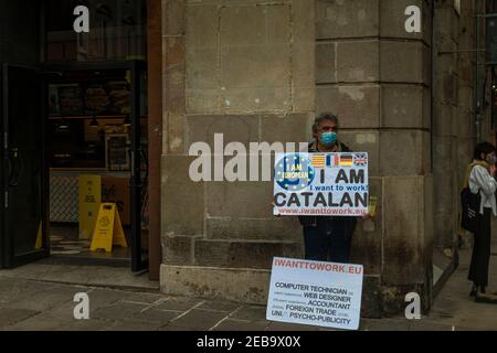 Barcelona, Spain. 12th Feb, 2021. An unemployed protestor is seen with his placards in Barcelona's Gothic quarter Credit: Matthias Oesterle/Alamy Live News Stock Photo