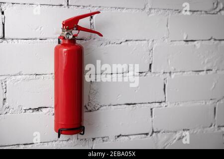 blank red fire extinguisher hanging on white brick wall. copy space Stock Photo