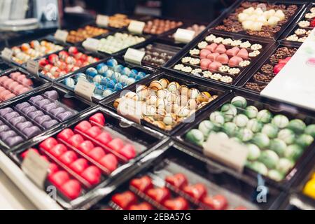 Assortment of chocolate colorful candies desserts on cafe showcase. Variety of sweets with different flavours nuts spices in store. Confectionery Stock Photo