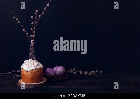 Easter cakes on a dark background, decorated with marshmallows and painted Easter eggs in a wicker nest. Stock Photo