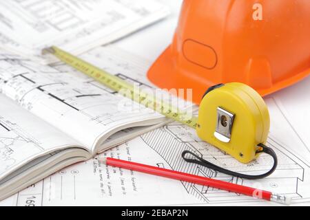 Construction safety helmet posed on architectural blueprints, tape measure in close-up, a pencil . Concept of architecture and construction of the bui Stock Photo