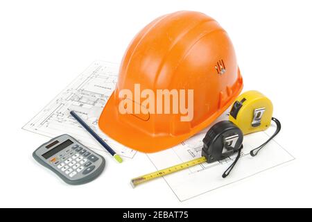 Concept of architecture and construction of the building with hard hat posed on paper plans, tape measures, a pencil and a calculator. photo shooting Stock Photo