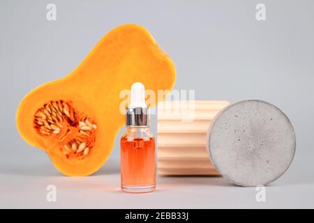 Still life composition with dropper bottle of natural organic cosmetics - pumpkin seeds oil extract for skincare or hair with pumpkins and plaster Stock Photo