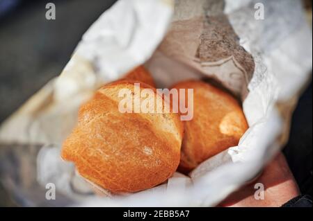 View into an open paper bag with fresh buns that is held in hands. Stock Photo