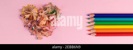 Banner with sharpened colored pencils and heart-shaped pencil shavings. Rainbow or LGBT pencils. Decoration for St. Valentine's Day. Top view