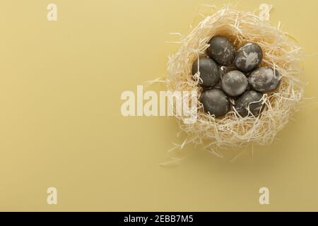 Silver easter eggs in straw nest, easter nest isolated on yellow background Stock Photo