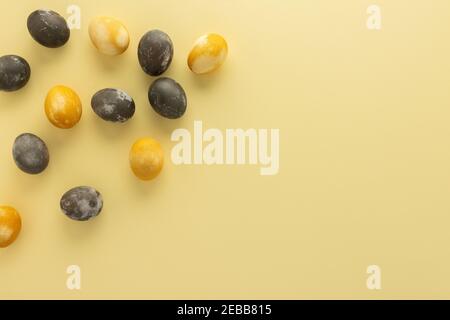 Golden and silver easter eggs scattered on yellow background, festive easter concept Stock Photo