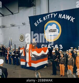 Trip to Western States: Visit to the Pacific Fleet, President Kennedy aboard the USS Kitty Hawk, 5:00PM. President John F. Kennedy (at podium) delivers remarks aboard the aircraft carrier USS Kitty Hawk (CVA-63), after viewing U.S. Pacific Fleet demonstrations at sea off the coast of San Diego, California. Also pictured (standing right of podium): Naval Aide to the President, Captain Tazewell T. Shepard, Jr.; Commander of Carrier Division One, Rear Admiral Paul Masterton. Stock Photo