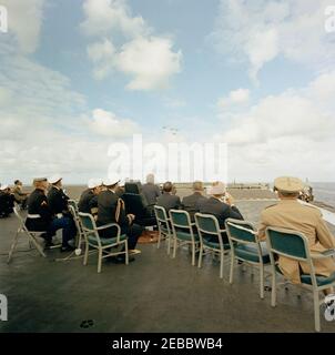 Trip to Western States: Visit to the Pacific Fleet, President Kennedy aboard the USS Kitty Hawk, 5:00PM. President John F. Kennedy (seated in high-back chair at center, back to camera) and other distinguished guests watch U.S. Pacific Fleet demonstrations from the flight deck of the aircraft carrier USS Kitty Hawk (CVA-63), at sea off the coast of San Diego, California. Seated right of President Kennedy (left to right): Governor of California, Edmund G. u0022Patu0022 Brown; Senator Clair Engle (California); Under Secretary of the Navy, Paul u0022Redu0022 Fay; Commandant of the Marine Corps Stock Photo