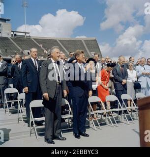 Inspection tour of NASA installations: Houston, Texas, motorcade, address at Rice University, 9:34AM. President John F. Kennedy waves from the speakersu0027 platform at Rice University Stadium, Houston, Texas. President of Rice University, Dr. Kenneth S. Pitzer, stands left of President Kennedy; platform guests stand in back. Stock Photo