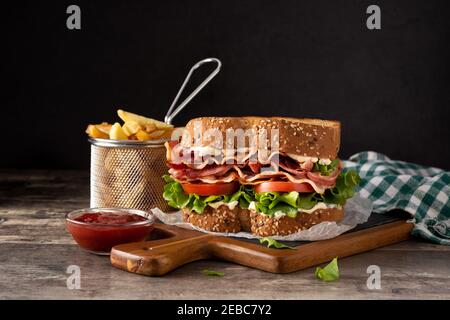 BLT sandwich and fries on wooden table Stock Photo