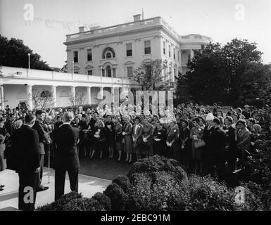 Visit of members of the New York Savings Banks Association, 9:20AM. President John F. Kennedy (left, at microphones) delivers remarks during a visit with members of the Savings Banks Association of New York State and their wives, following the groupu0027s tour of the White House. President of the Association, Alfred S. Mills (first from left), stands behind President Kennedy; others are unidentified. Rose Garden, White House, Washington, D.C. [Notes: Ink bleed-through in upper left portion of image is original to the file print.] Stock Photo