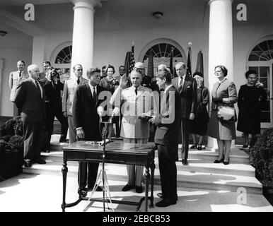 Swearing-in ceremony, Gen. Maxwell Taylor, Chairman, JCS, 12:00PM. President John F. Kennedy (center left) and others observe as General Maxwell D. Taylor (with right hand raised and left hand on Bible) is sworn in as Chairman of the Joint Chiefs of Staff (JCS); Attorney General, Robert F. Kennedy (center right, holding Bible), administers the oath of office. Looking on from the steps of the West Wing Colonnade, beginning at the very back (left to right): Military Aide to the President, General Chester V. Clifton; General Omar Bradley; Naval Aide to the President, Captain Tazewell T. Shepard, Stock Photo